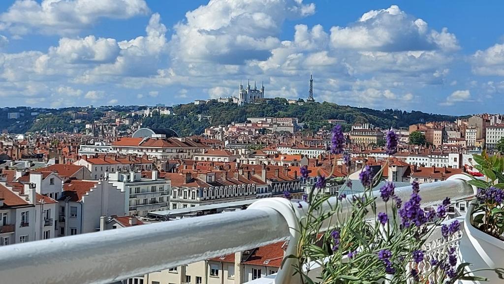 een balkon met paarse bloemen en uitzicht op de stad bij PLEIN SUD Terrasse Panoramique Climatisation Garage Netflix in Lyon