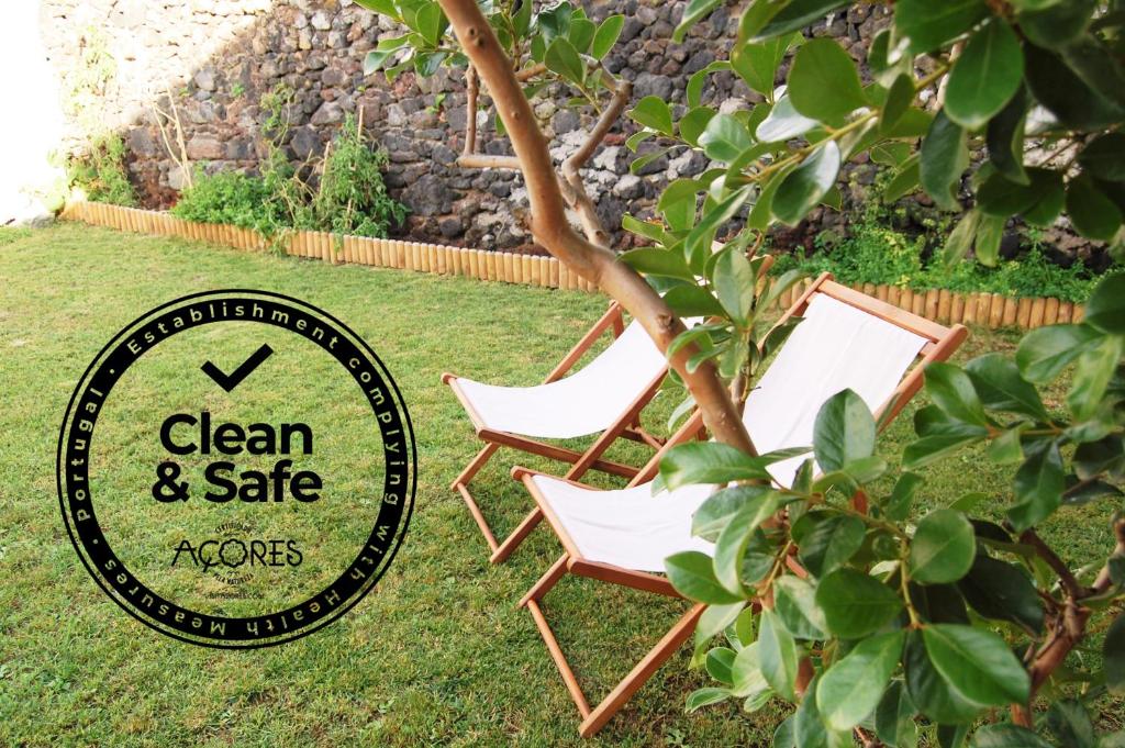 zwei Stühle im Gras neben einem Schild in der Unterkunft Verde'Água Family Home in Mosteiros