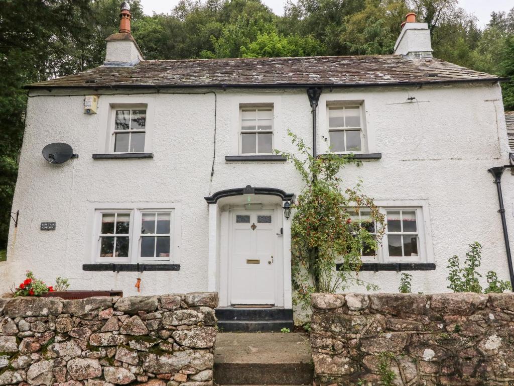 a white house with a stone wall at Yew Tree Cottage in Ravenglass