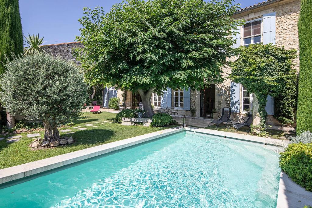 una piscina frente a una casa con árboles en Les volets bleus-Maillane, en Maillane