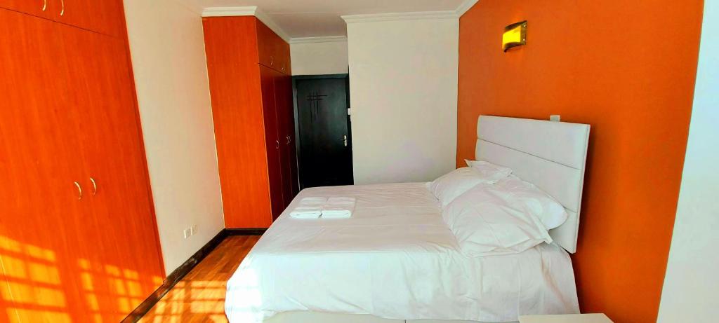 Bett in einem Zimmer mit orangefarbener Wand in der Unterkunft Pleasant Nest Homestay near JKIA Airport and SGR Station Nairobi in Nairobi