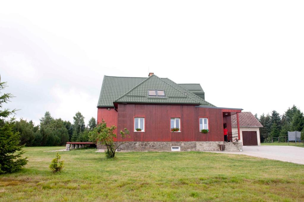 eine rote Scheune mit einem grünen Dach auf einem Feld in der Unterkunft Penzion Hájovna in Klíny
