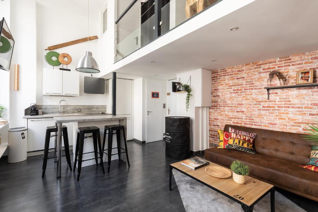 a living room with a couch and a brick wall at DIFY Boileau - Foch in Lyon