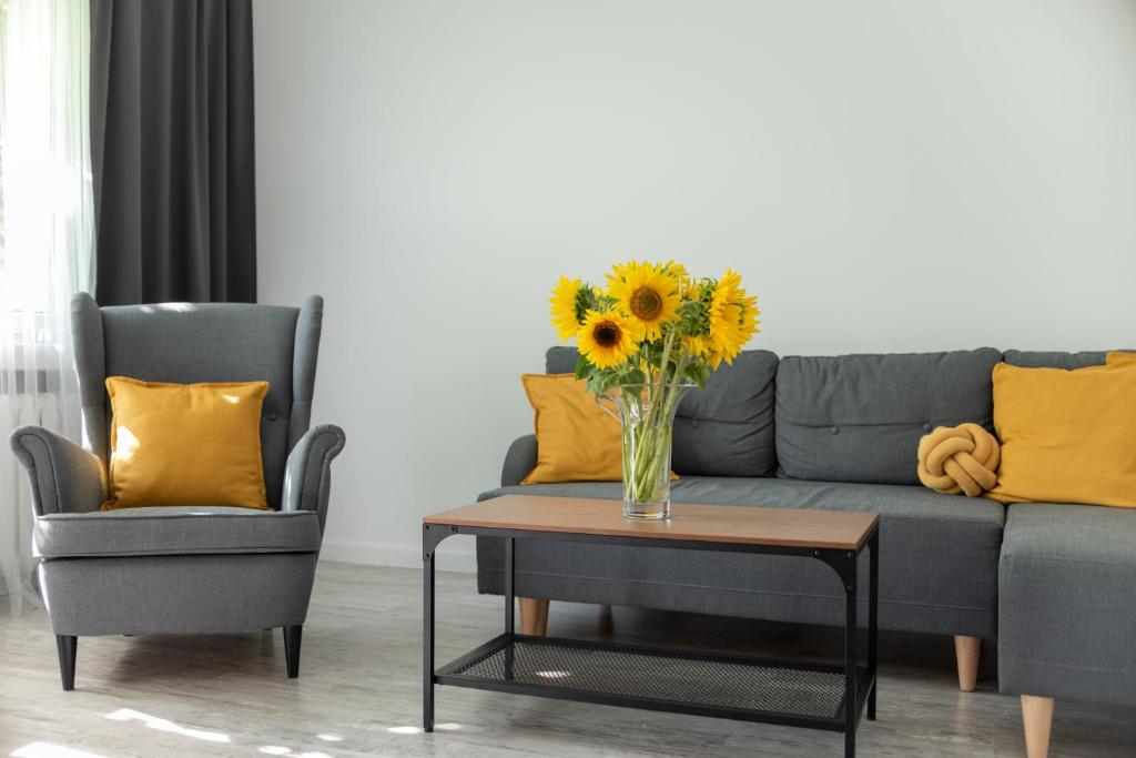 a vase of sunflowers sitting on a coffee table next to two chairs at Apartament BLISKO WSZĘDZIE in Ostrowiec Świętokrzyski