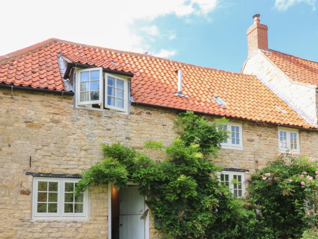 een stenen huis met een rood dak bij Kings Cottage in Grantham