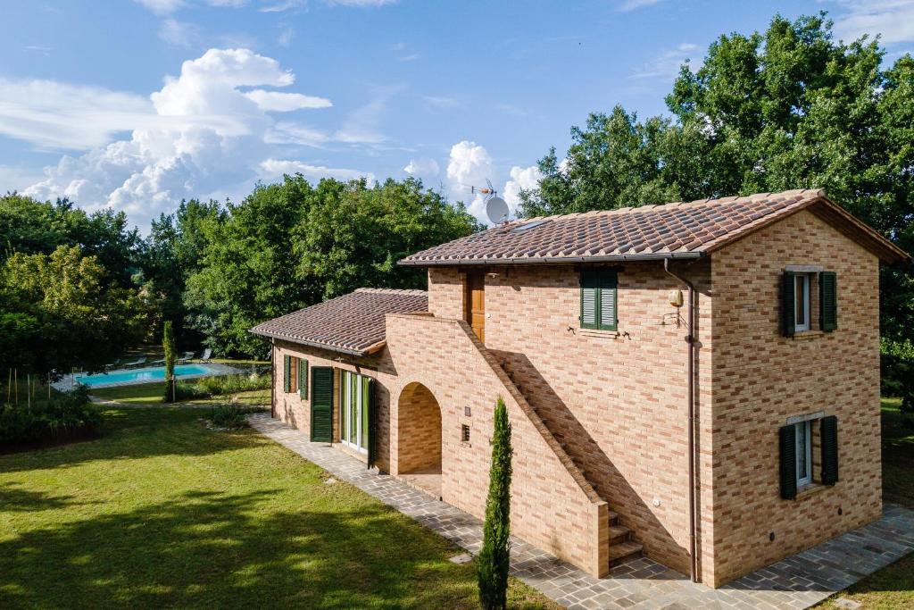 une maison en briques avec une piscine en arrière-plan dans l'établissement Casa Ilenia, à Marciano Della Chiana