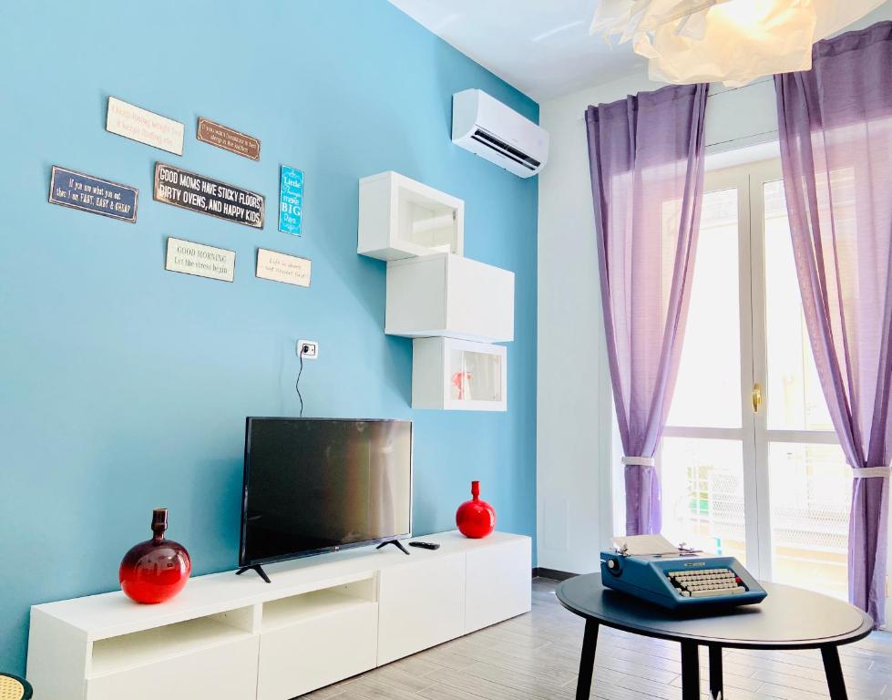 een woonkamer met een tv aan een blauwe muur bij CASA di Ale & Frank in Salerno