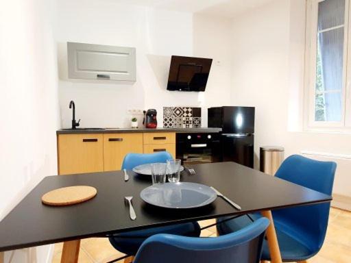 een keuken met een zwarte tafel en blauwe stoelen bij Superbe Appartement de 50m2 in Graulhet