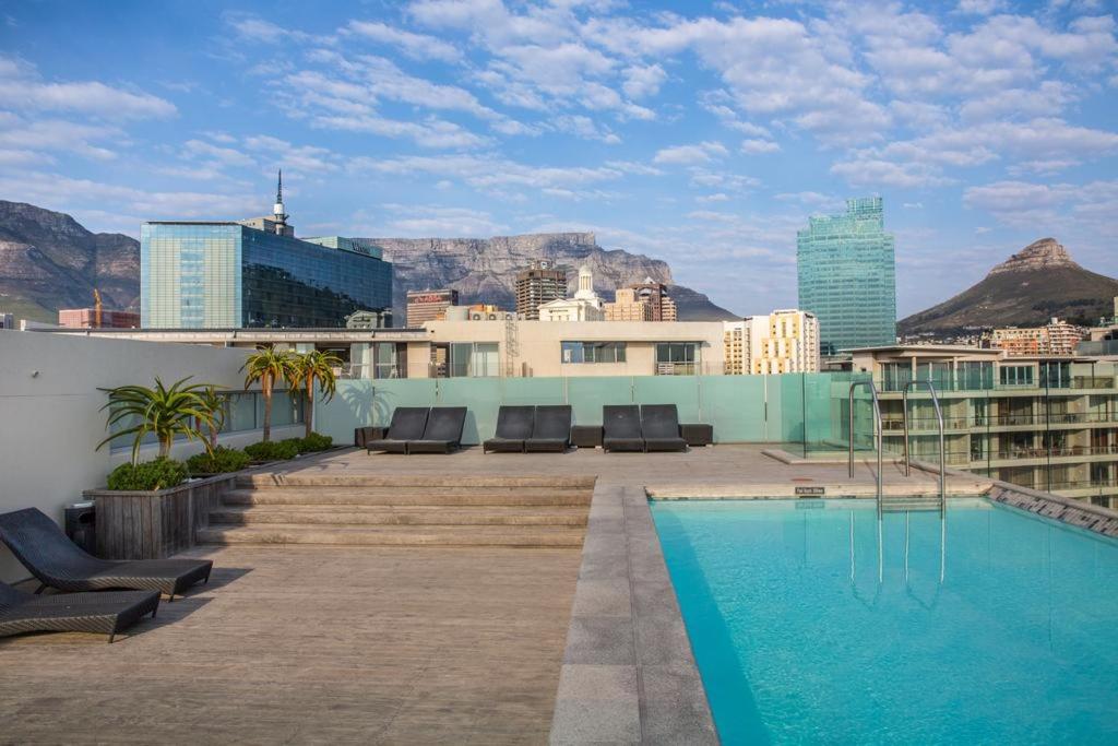 a swimming pool on the roof of a building with mountains at Harbour Bridge Waterfront in Cape Town