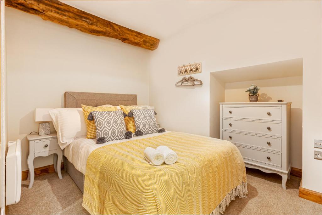 a bedroom with a bed with a yellow blanket and a dresser at Guest Homes - The Merchant House Apartments in Hereford