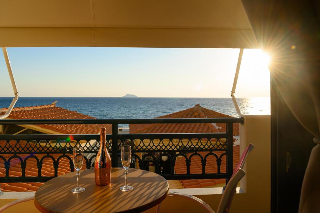 una mesa con 2 vasos en un balcón con vistas al océano en Studios Paradise, en Kalamaki