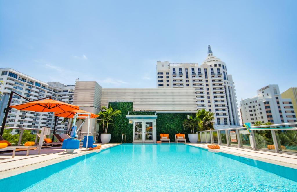 a pool with chairs and an umbrella and buildings at Berkeley Shore Hotel in Miami Beach