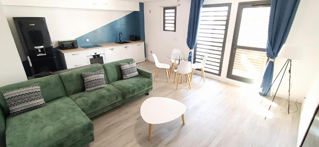 een woonkamer met een groene bank en stoelen bij Le Clipper in Saint-Pierre