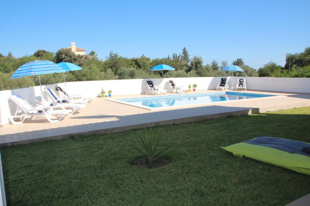 a swimming pool with chairs and umbrellas in a yard at Villa Olive in Loulé