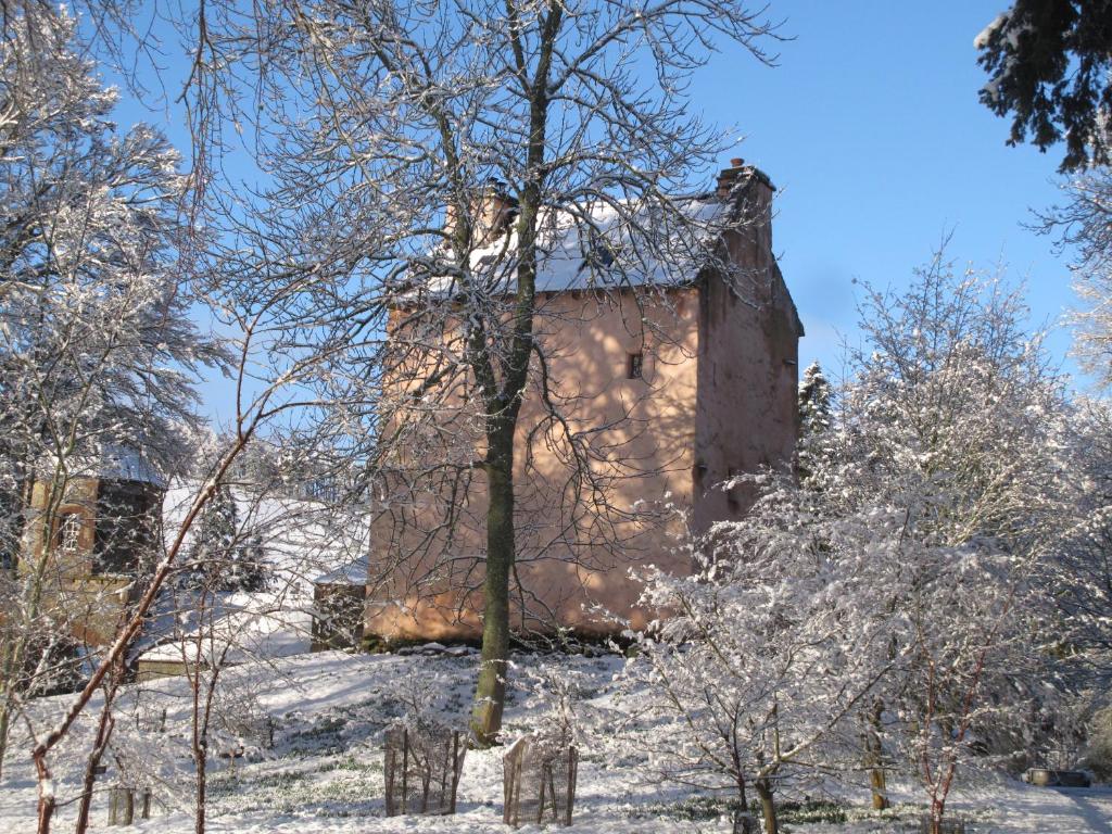 ein Gebäude auf einem Hügel mit schneebedeckten Bäumen in der Unterkunft Barns Tower in Peebles