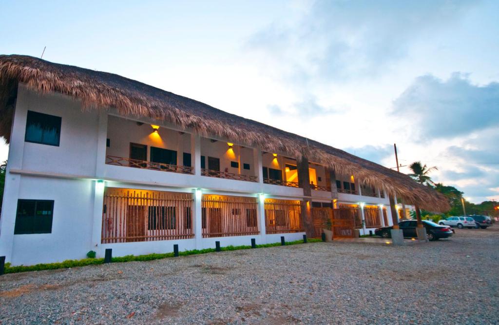 a large white building with a thatched roof at Casa Mandala Hotel in Pijijiapan
