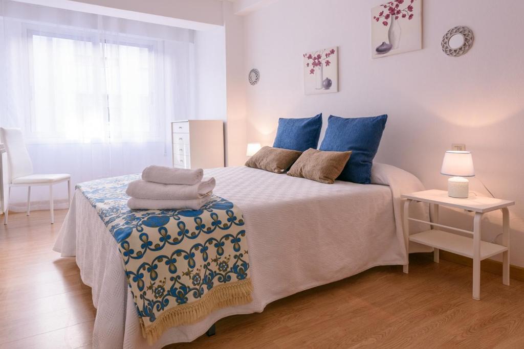 a bedroom with a bed with blue pillows on it at Apartamento Centro Santiago in Santiago de Compostela