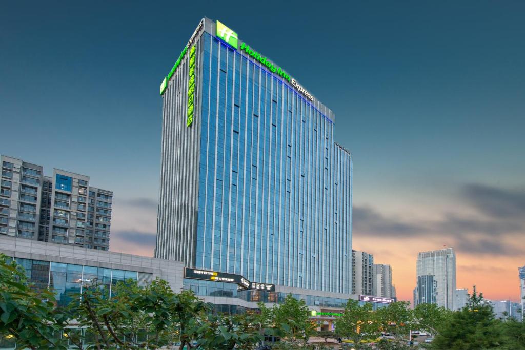 un edificio alto con una señal verde encima en Holiday Inn Express Jinan High-Tech Zone, an IHG Hotel en Jinan
