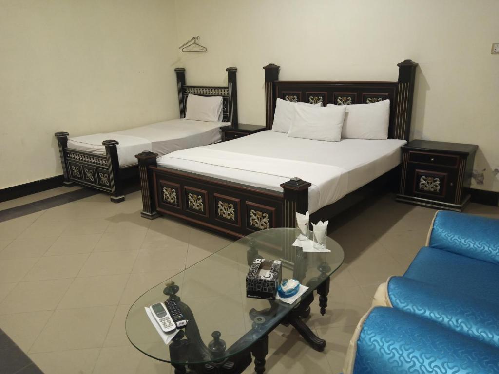 a hotel room with two beds and a glass table at Hotel VIP Palace Lodge in Multan