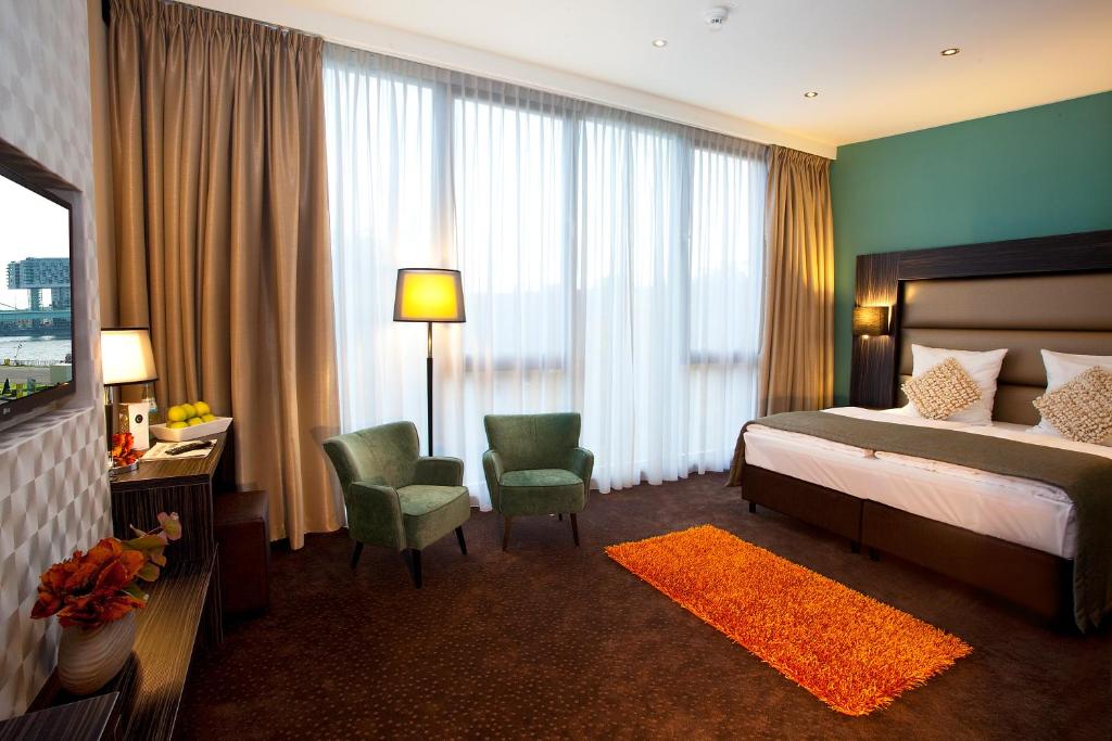 ケルンにあるCentro Hotel Ayun DELUXEのベッドとテレビが備わるホテルルームです。