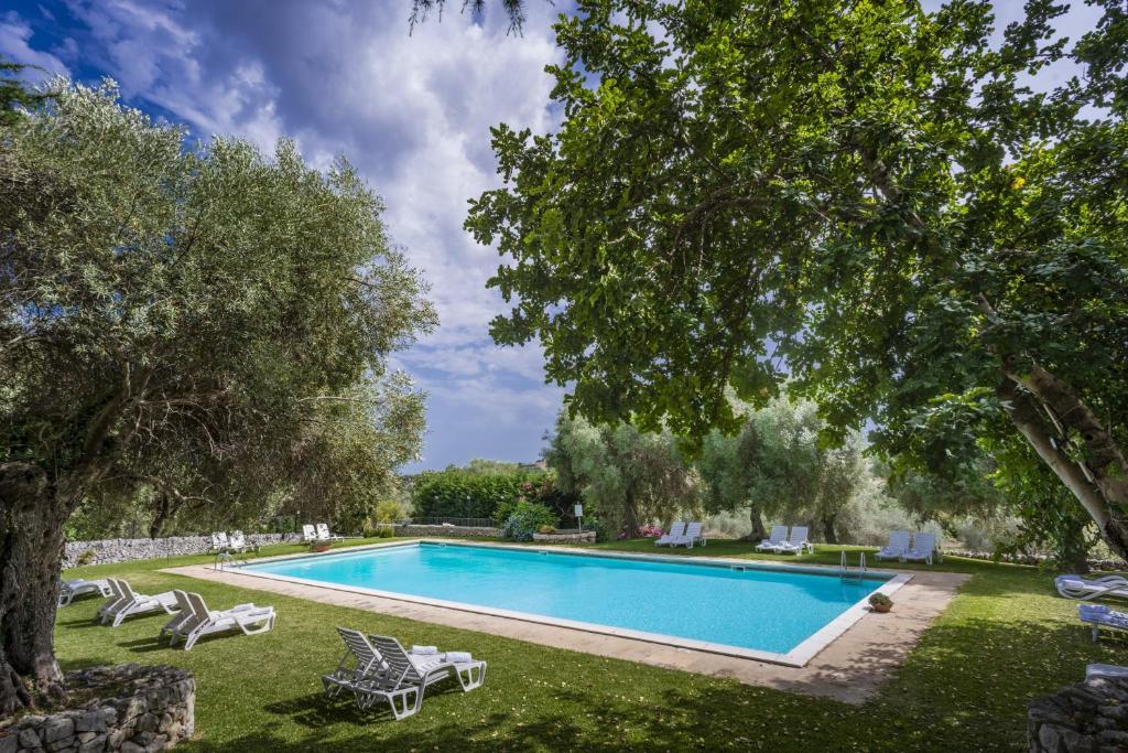 a swimming pool in a yard with chairs and trees at Agriturismo Borgo degli ulivi in Canicattini Bagni