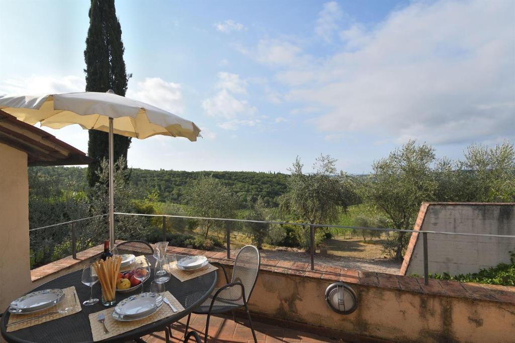 a table with an umbrella and chairs on a balcony at Il Sole in Gaiole in Chianti