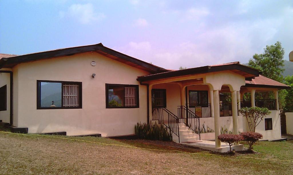 Cette petite maison blanche dispose d'une terrasse couverte. dans l'établissement Portersville Private Lodge, à Freetown