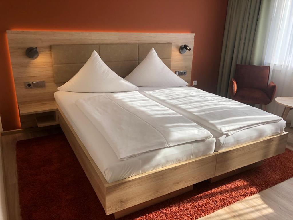 een slaapkamer met een groot bed met witte lakens bij Hotel Wilms in Keulen