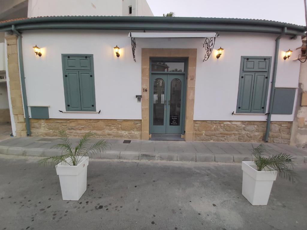 a building with two green doors and two potted plants at Magdalene's City House Inn in Larnaka