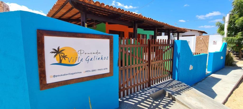 une clôture bleue avec un panneau devant un bâtiment dans l'établissement Pousada Villa Galinhos, à Galinhos