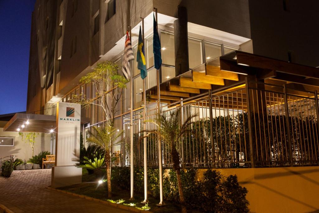 un edificio con banderas delante de él por la noche en São Carlos Marklin Suítes, en São Carlos