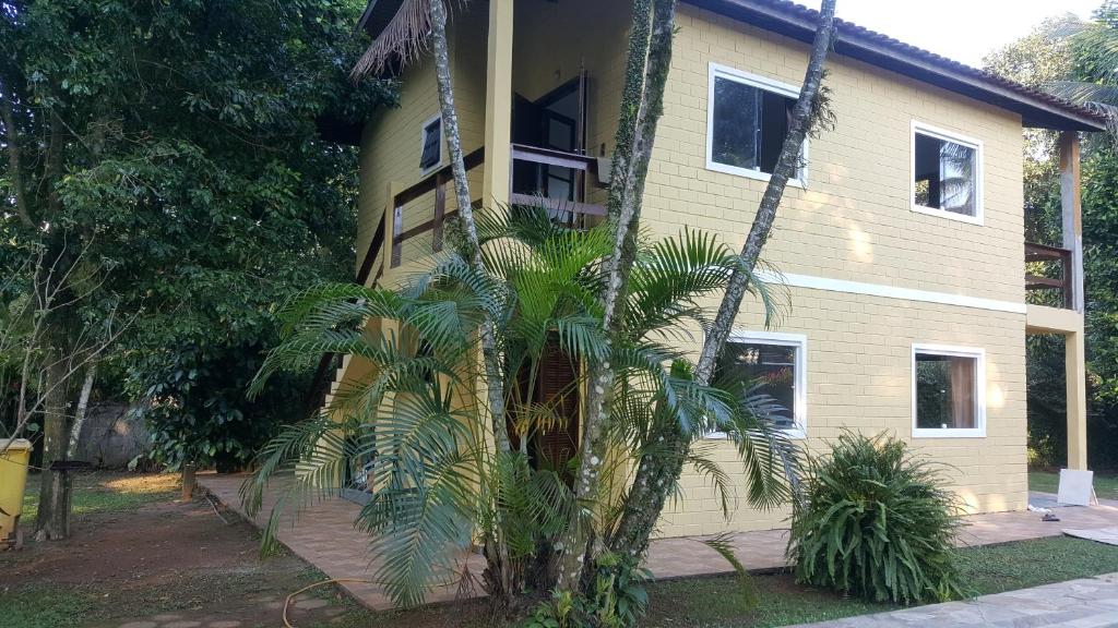 a house with a palm tree in front of it at Vila da Praia in Boicucanga