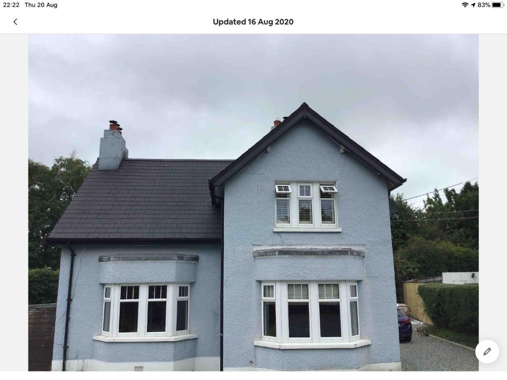 a blue house with two windows and a chimney at The Blue Cottage in Antrim