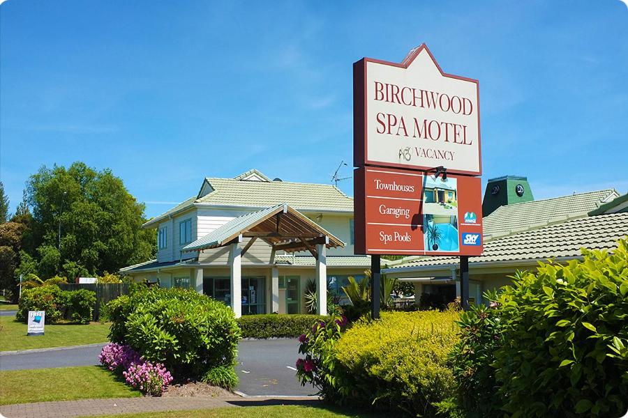 a sign in front of a house with a sign at Birchwood Spa Motel in Rotorua