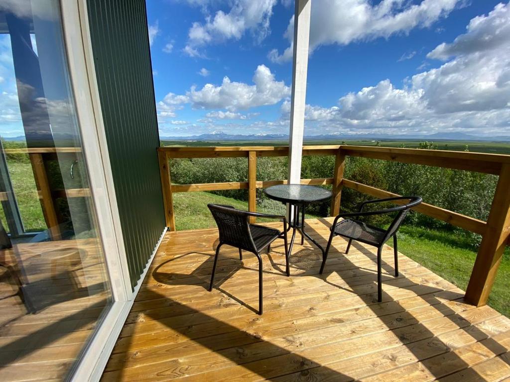 a balcony with two chairs and a table on a deck at Skeiðvellir Panorama house in Hella