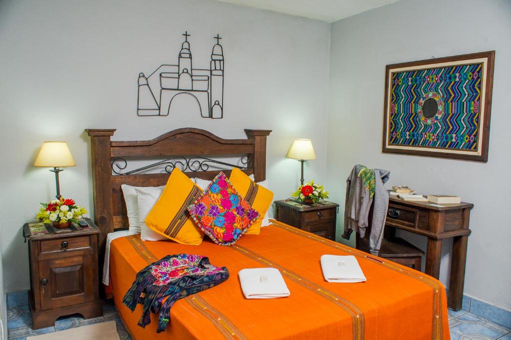 1 dormitorio con 1 cama con sábanas de color naranja y escritorio en Hotel Casa Rustica by AHS, en Antigua Guatemala