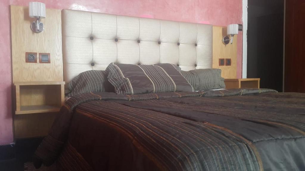 um quarto com uma cama grande e uma grande cabeceira. em HOTEL VELLEDA em Rabat