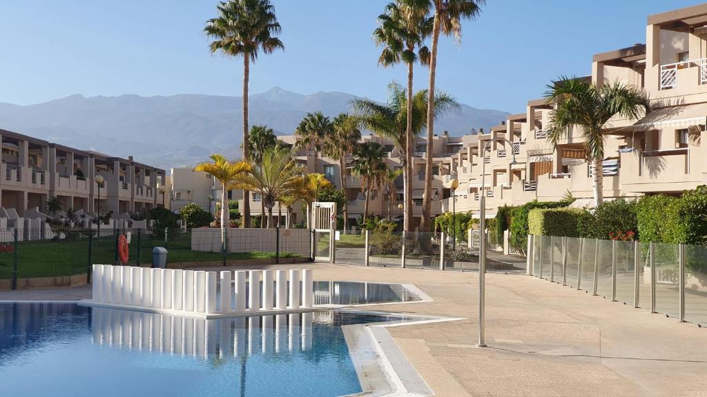 uma piscina numa cidade com palmeiras e edifícios em Friendly Tejita em Granadilla de Abona
