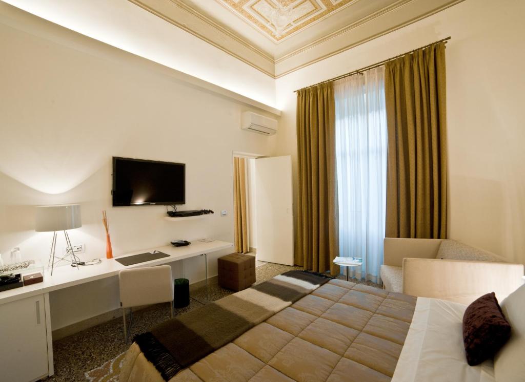レッジョ・ディ・カラブリアにあるTown House Cavourのベッド、デスク、テレビが備わるホテルルームです。