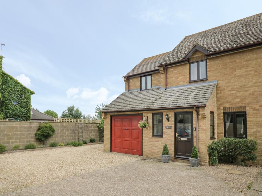 a brick house with a red garage at Kite Cottage in Brackley