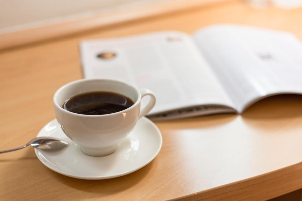 a cup of coffee on a table next to an open book at Ibis Hong Kong Central & Sheung Wan in Hong Kong