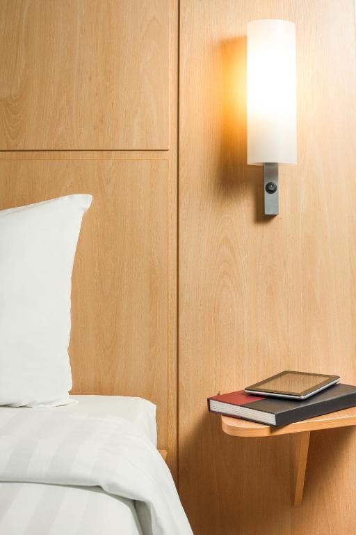 a bed with a book on a table next to a lamp at Ibis Hong Kong Central & Sheung Wan in Hong Kong