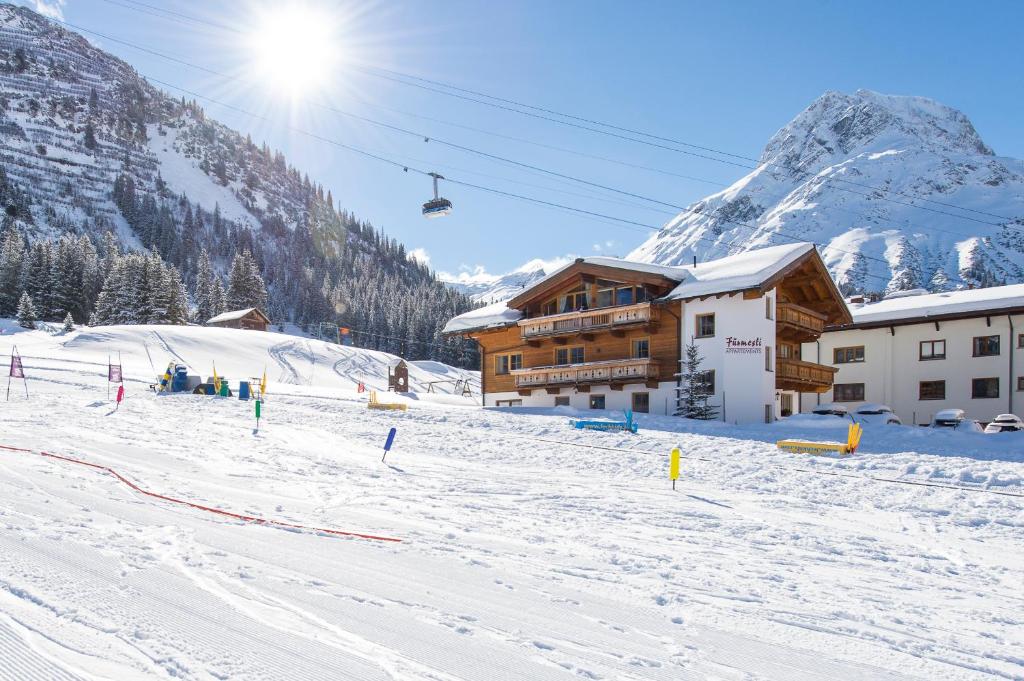a ski slope with a ski lodge and a ski lift at Fürmesli Appartements in Lech am Arlberg