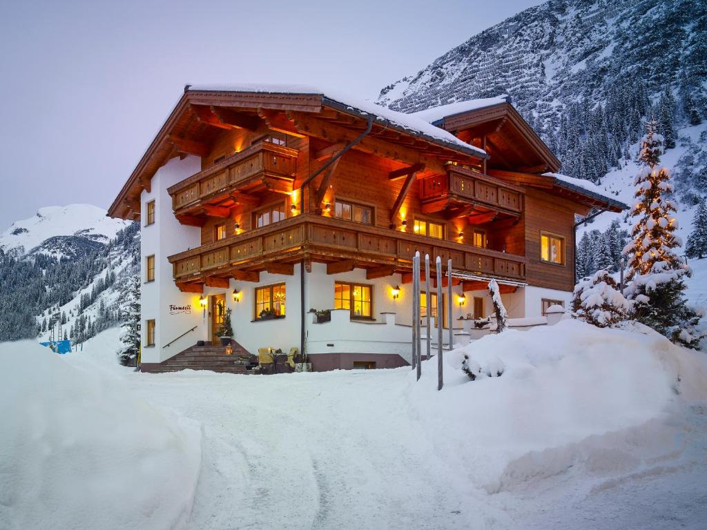 a large wooden house in the snow in the mountains at Fürmesli Appartements in Lech am Arlberg