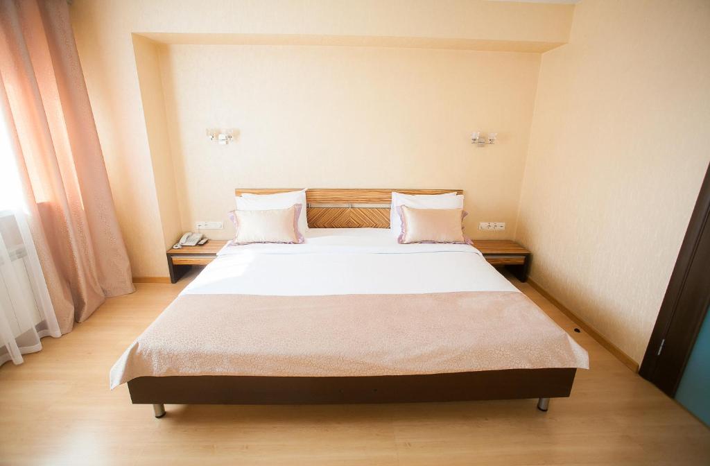 a bedroom with a large bed with white sheets and pillows at AZIMUT Hotel Siberia in Novosibirsk