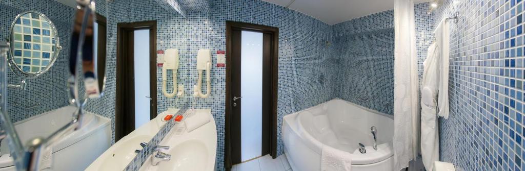 a blue tiled bathroom with a tub and a sink at AZIMUT Hotel Siberia in Novosibirsk