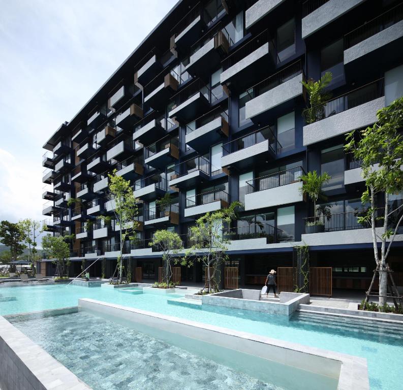 an apartment building with a swimming pool in front of it at Seamira House Huahin - SHA in Hua Hin
