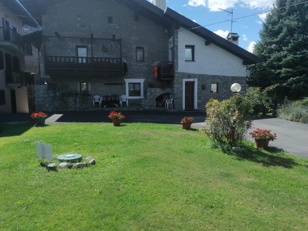 a large stone house with a yard with grass and flowers at Casa D'antan Gressan in Aosta