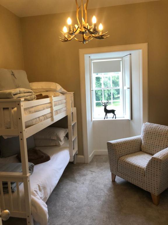 ホーイックにあるBranxholme Castle (Bed & Breakfast)の二段ベッド1組、椅子、窓が備わる客室です。