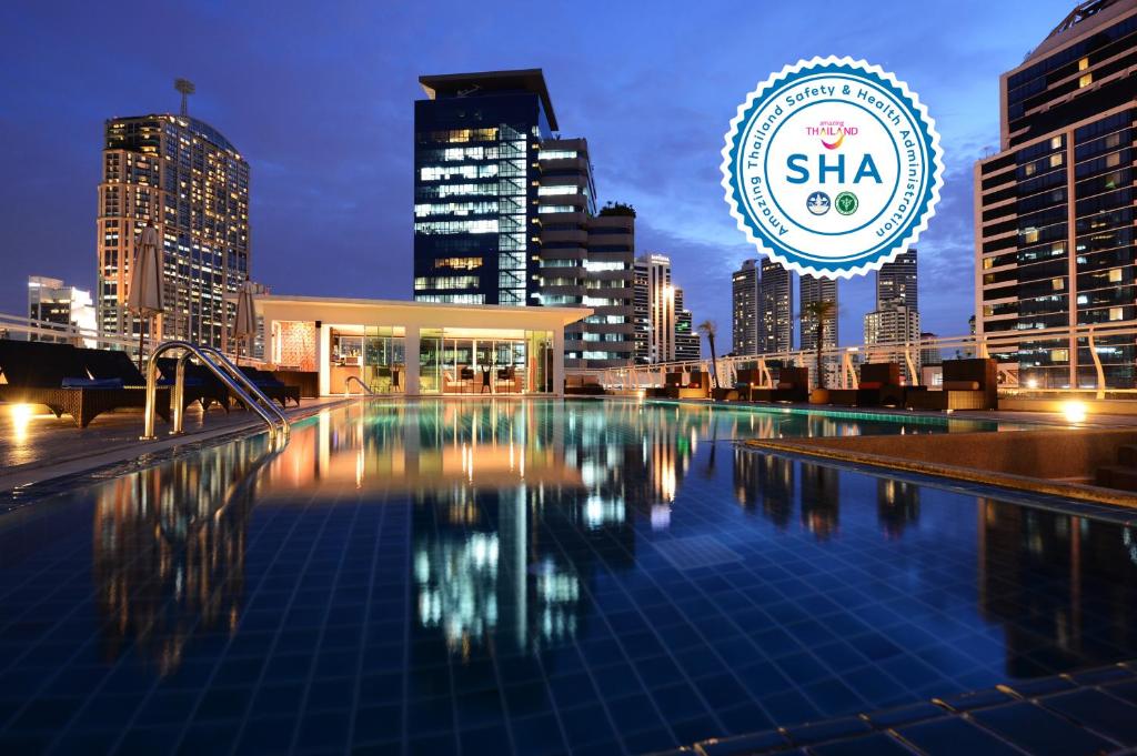 een zwembad met een skyline van de stad op de achtergrond bij The Bless Hotel and Residence in Bangkok